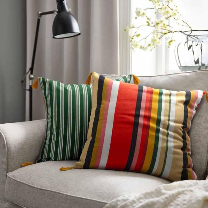 Colorful striped pillows on a gray sofa with a lamp and window in the background
