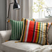 Colorful striped pillows on a gray sofa with a lamp and window in the background