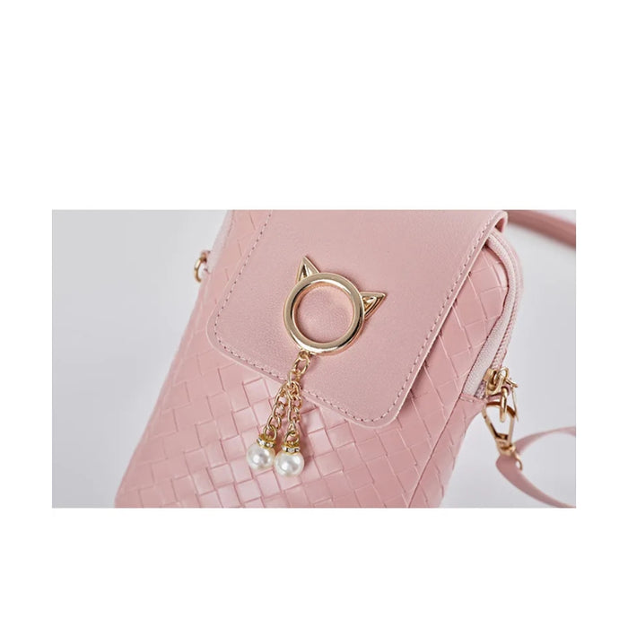 Pink handbag with a gold cat ear charm and pearl details on a light gray background