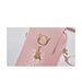 Pink handbag with a gold cat ear charm and pearl details on a light gray background
