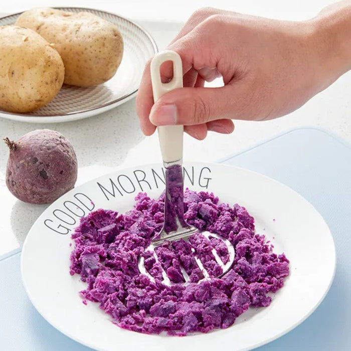 Stainless steel potato masher – hand mashing vibrant purple sweet potatoes on “GOOD MORNING” plate