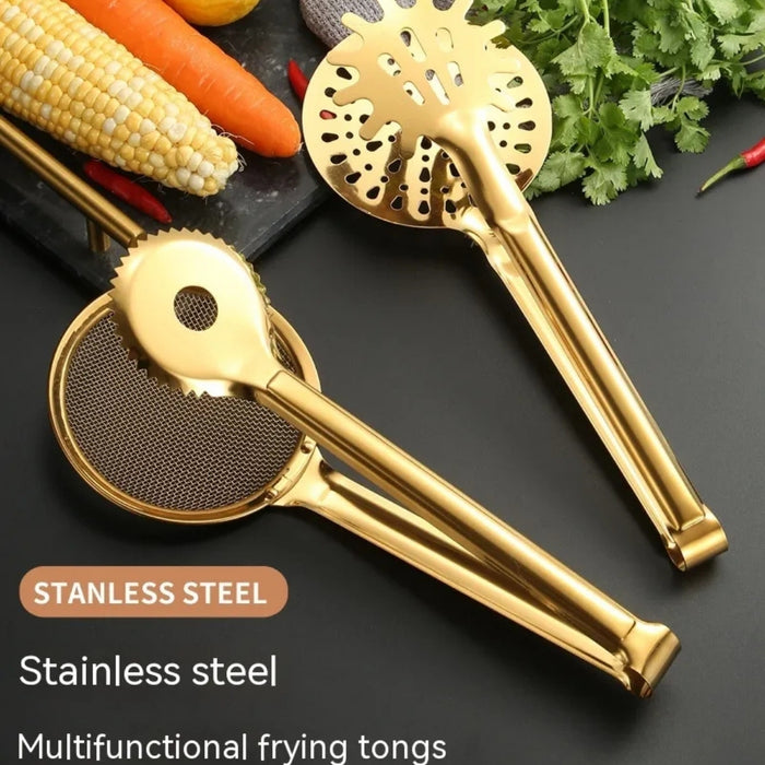 Two golden stainless steel multifunctional frying tongs displayed on a black surface. One features a perforated skimmer head with round and oval holes, while the other showcases a mesh strainer basket with a serrated edge for secure gripping. Both have long, glossy handles, surrounded by fresh vegetables—corn, carrots, cilantro—and are captioned with the text: “STANLESS STEEL – Stainless steel – Multifunctional frying tongs,” emphasizing versatility and premium design -1600003112383 13034147.