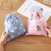 Two drawstring bags held over a wooden surface, one blue with daisies, one pink with cartoon dinosaurs – 1598445710448 14078092