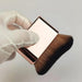  Close-up of gold makeup brush held in gloved hand highlighting bristle density