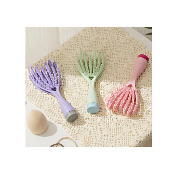 Three pet grooming tools in purple, green, and pink on a textured surface.