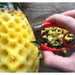 Person using a red tool to cut a pineapple on a wooden surface
