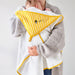Baby wearing a white and yellow striped hooded towel with a logo, held by an adult against a plain background.