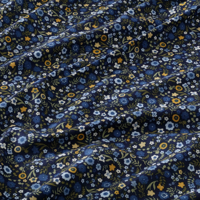 Floral patterned fabric with blue, yellow, and white flowers on a dark blue background.