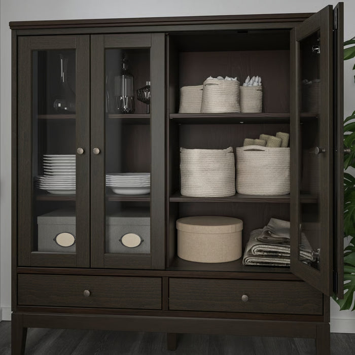 Dark wooden cabinet with open doors displaying various items including plates, baskets, and folded clothes.