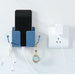 Blue wall-mounted charging stand with smartphone placed inside; side hooks hold a white earphone cable and a black wristwatch—connected to a wall socket with a charging cable, showcasing organized multi-use storage – 1598448185067 13069398.