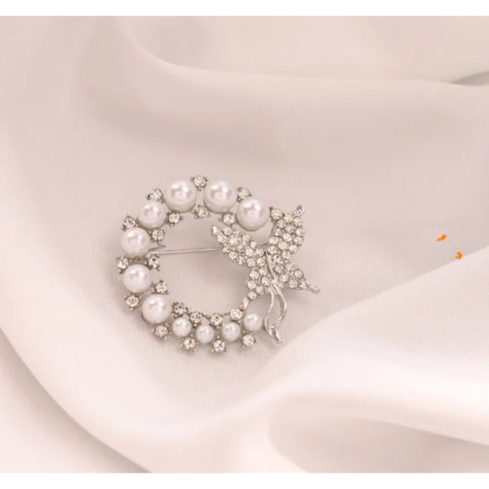 Pearl wreath brooch with a bow on a light pink fabric background