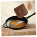 Frying pan with a brown spatula on a wooden surface
