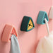 Three colorful wall hooks on a pink background