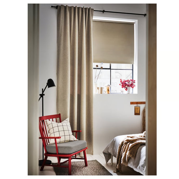 Red chair with gray cushion in a room with beige curtains and a window.