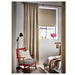 Red chair with gray cushion in a room with beige curtains and a window.
