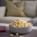 IKEA VITBLECKA serving bowl – light grey bowl with popcorn, placed on textured mat beside maroon napkins and sofa - 30610090