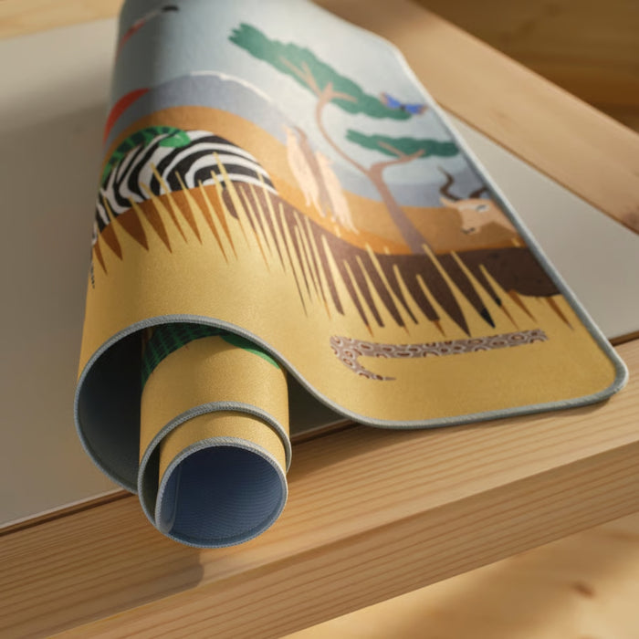 Rolling out a yoga mat with a nature-themed design on a wooden surface