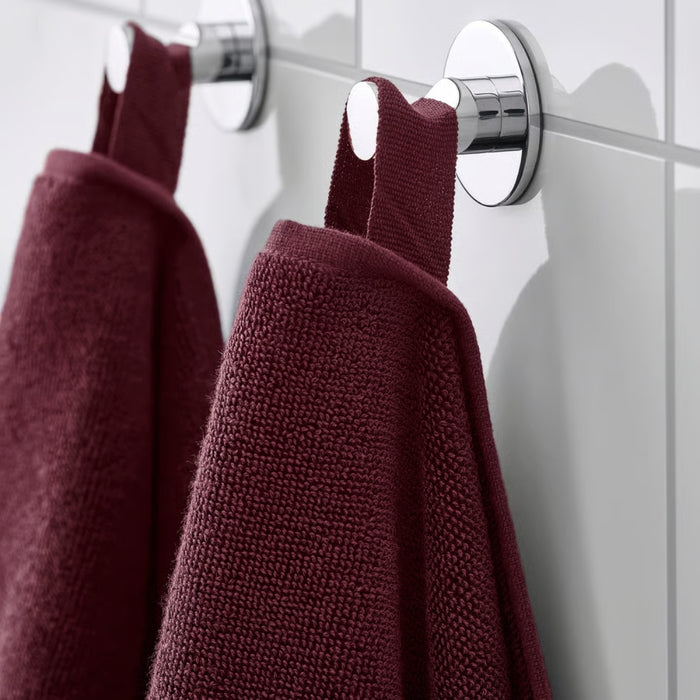 Two IKEA FREDRIKSJÖN washcloths in deep red, 30x30 cm (12x12") hanging by fabric loops on chrome hooks against white tiled wall – elegant and organized bathroom setup with rich maroon contrast - 70552762