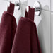 Two IKEA FREDRIKSJÖN washcloths in deep red, 30x30 cm (12x12") hanging by fabric loops on chrome hooks against white tiled wall – elegant and organized bathroom setup with rich maroon contrast - 70552762