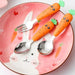 Children’s carrot-themed tableware set displayed on a pink bunny-face plate with carrot illustrations—includes a stainless steel fork and two spoons with bright orange handles shaped like carrots, each topped with a smiling face and green leafy detail; playful, kid-friendly design enhances mealtime enjoyment – 1600002332714 12850097.
