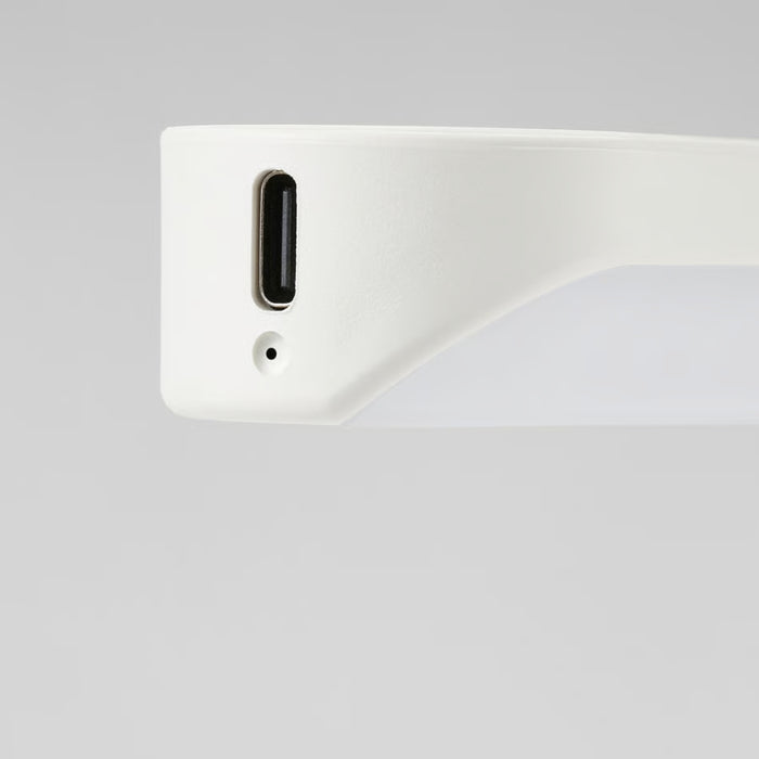 Close-up of a white electronic device with a USB-C port on a light gray background