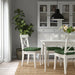 Dining room with white chairs, green cushions, and a black pendant light.