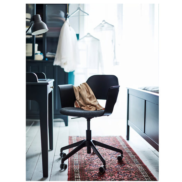 Black office chair in a modern office setting with desks and clothing in the background.