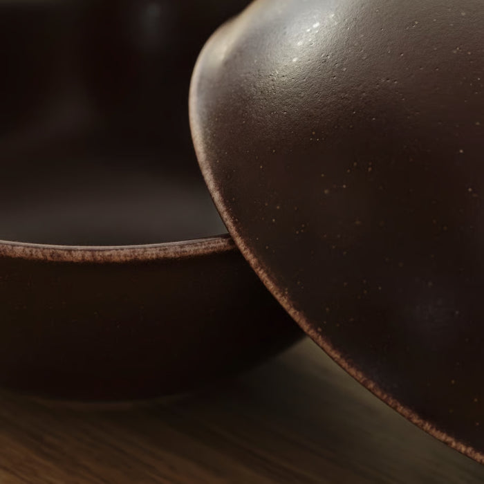 Close-up of a dark brown leather-bound book on a wooden surface with a blurred background