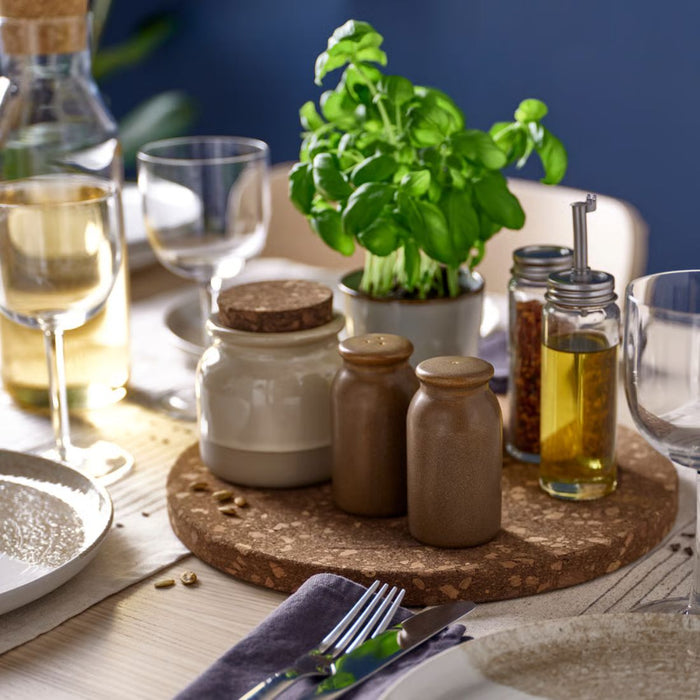 Table setting with jars, a plant, and glasses on a wooden board.