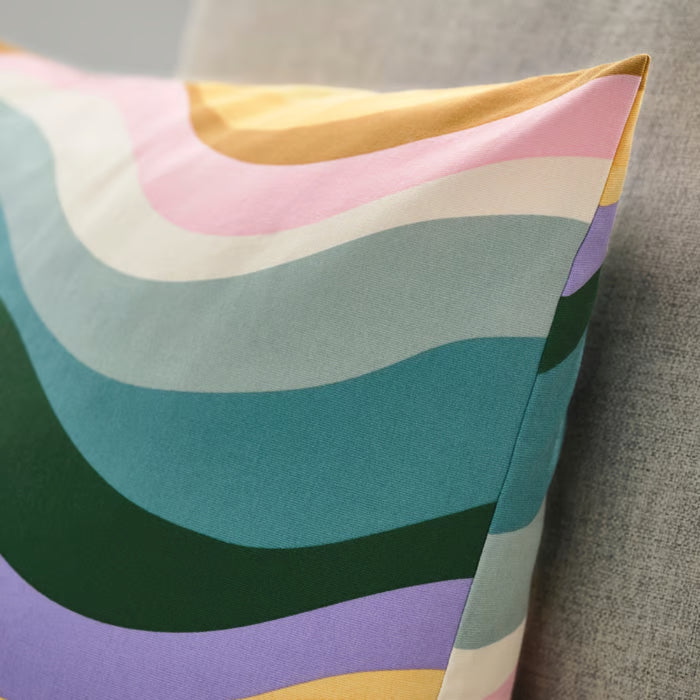 IKEA MYGGBLOMSTER cushion cover with vibrant multicolour wavy stripes on grey-blue base, styled on sofa for a lively, modern look – 50582133