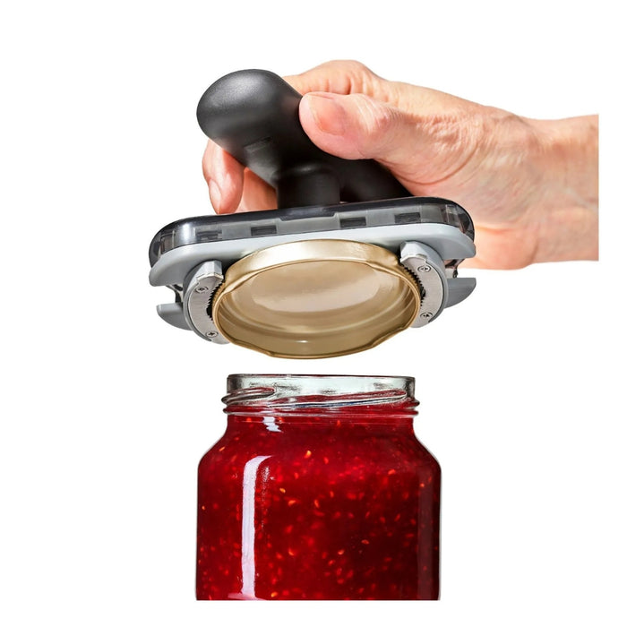 Hand using black-handled jar opener to twist open glass jar of red fruit preserves – ergonomic grip for sealed lids – 1600004084340 13927404