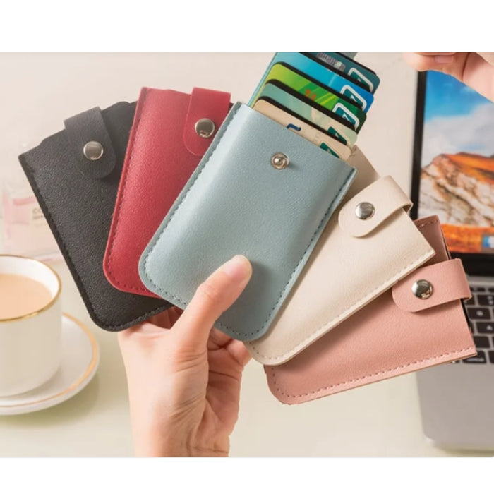 Hand holding a light blue cardholder with cards, surrounded by other cardholders in different colors on a desk.