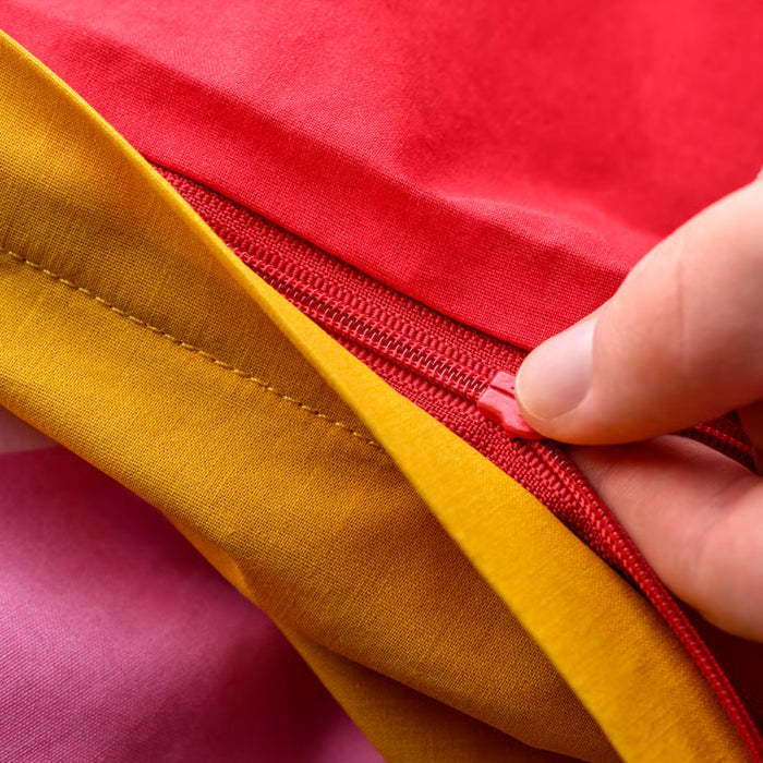 Close-up of a hand zipping a red and yellow garment together.
