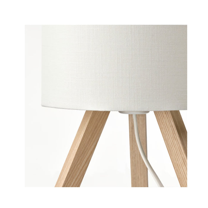 Table lamp with white fabric shade and wooden legs on a white background
