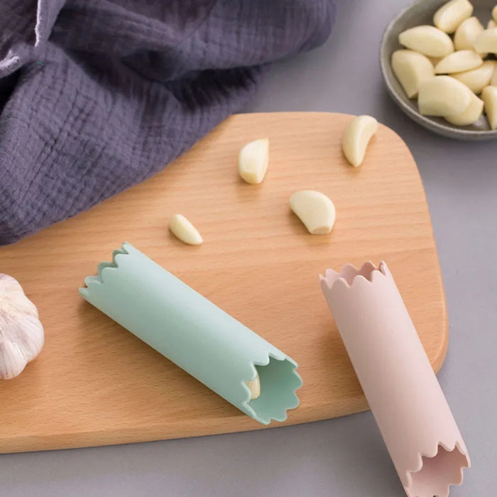 Two silicone garlic peeling tools on a wooden cutting board with garlic cloves.