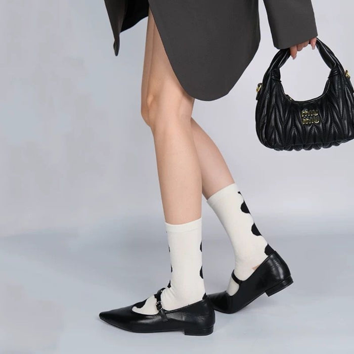 Person in oversized blazer wearing white socks with bold black polka dots and black shoes