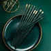 Green chopsticks with gold tips on a green plate against a matching background
