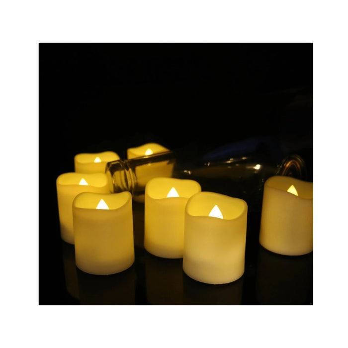 Flickering LED candles with a bottle in the background on a dark surface