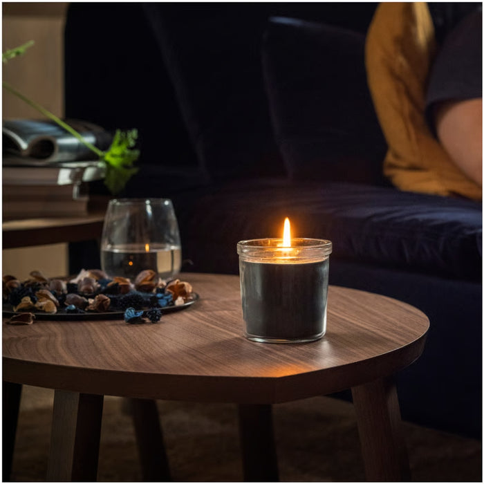 Candle in a glass jar on a wooden table with a blurred background