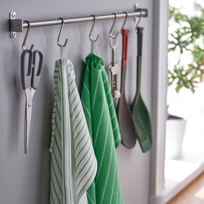 Kitchen utensils including scissors, spatulas, and green towels hanging on a rack.