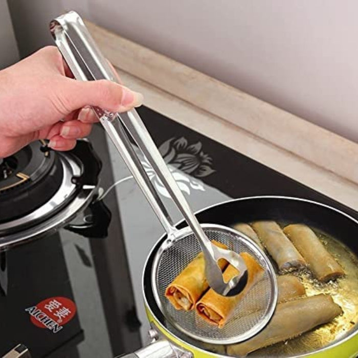 Person using tongs to handle food in a frying pan on a stove.