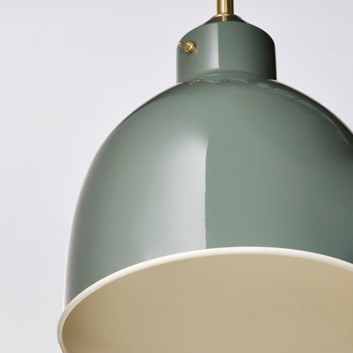 Close-up of RÖDFLIK pendant lamp showing brass fitting, toggle switch detail, and muted green conical top section