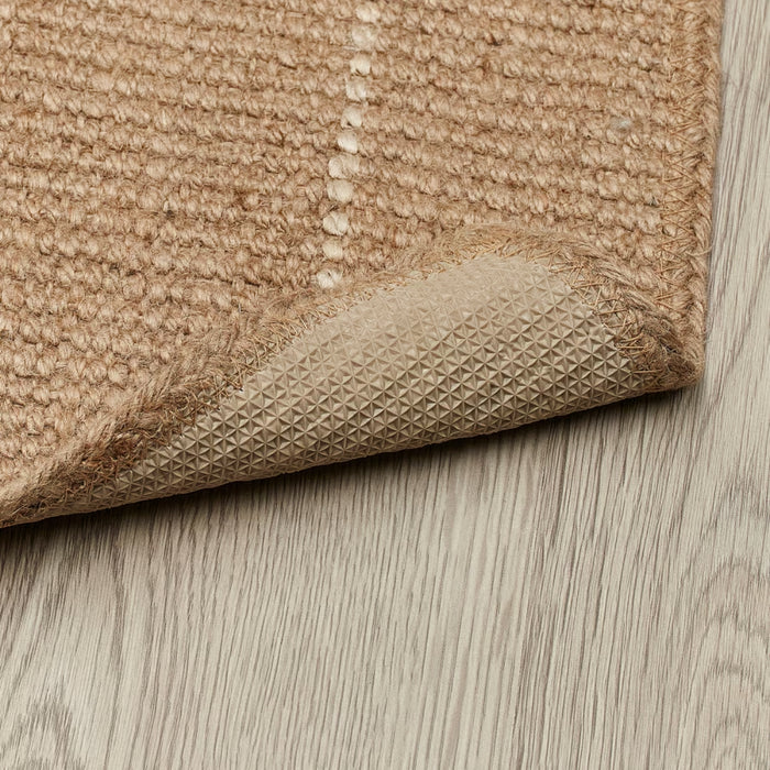 Close-up of a beige textured rug on a wooden floor