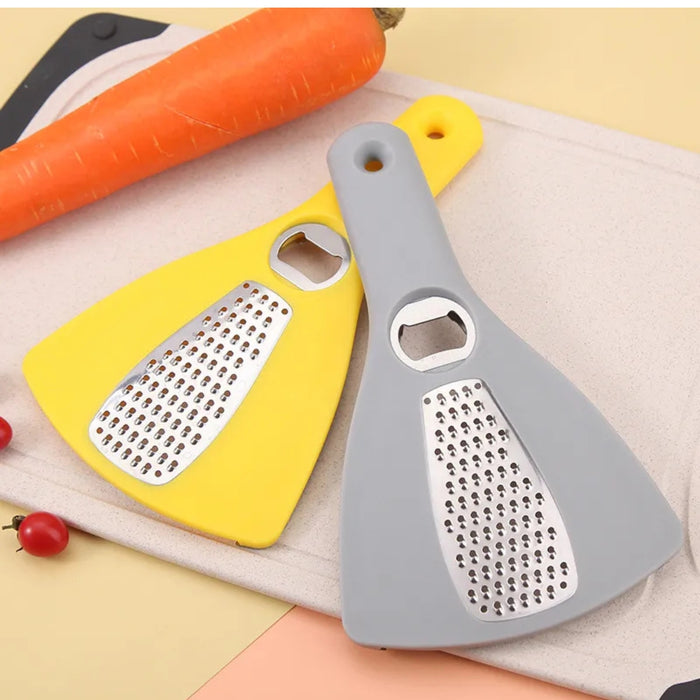 Two kitchen graters, one yellow and one gray, on a surface with vegetables.