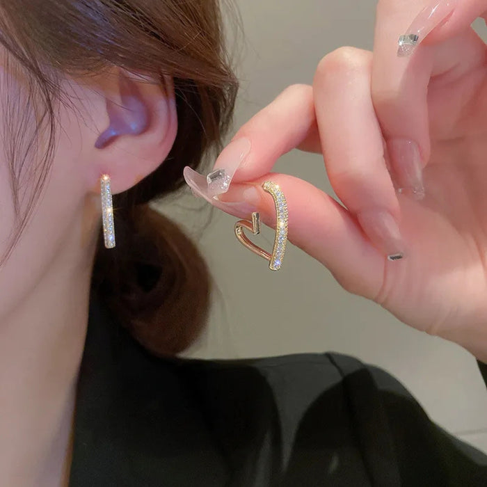 Gold hoop earrings being worn and held up to the ear.