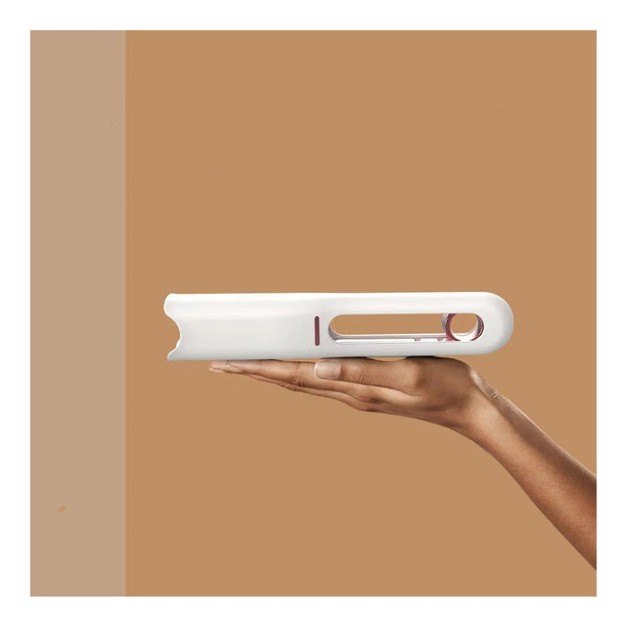 White hair straightener held in a hand against a brown background