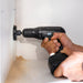 Hand using a cordless drill to make a hole in a wall.