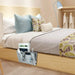 Bedroom with a bed and a bedside caddy holding books and other items.