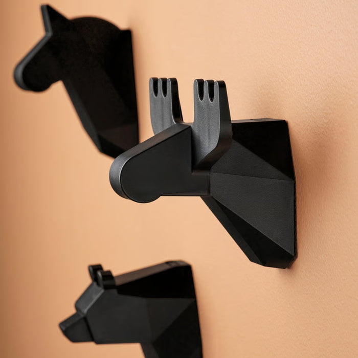 IKEA FRÖSÅDD black geometric hooks arranged vertically on peach wall, horse, moose, and bear design