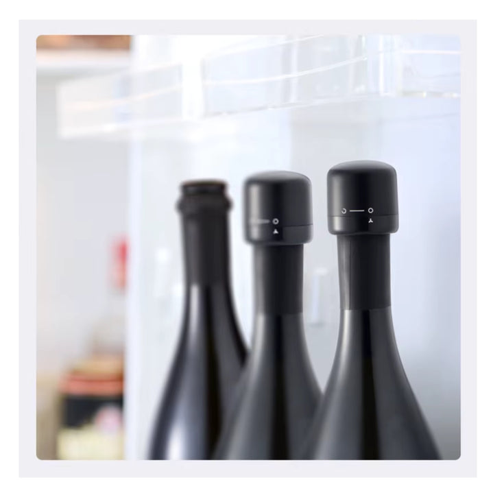 Three dark glass wine bottles with black screw caps and white adjustment markings, photographed inside a refrigerator shelf area.
